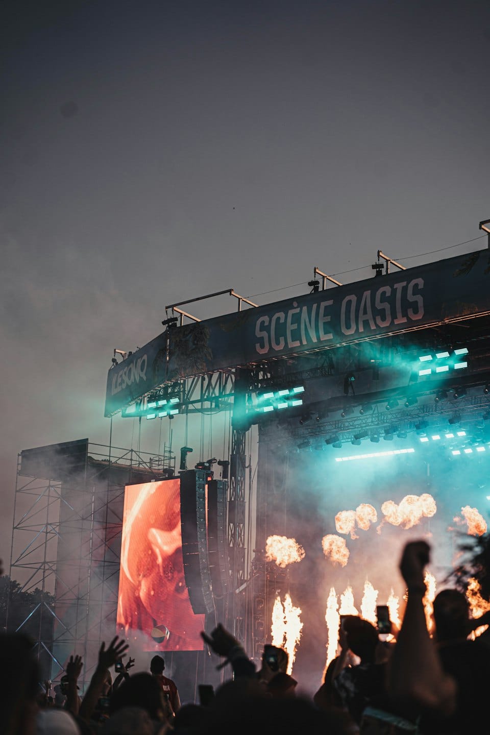 Publikum bei einem Musikfestival mit Pyrotechnik und Bühnenbeleuchtung.
